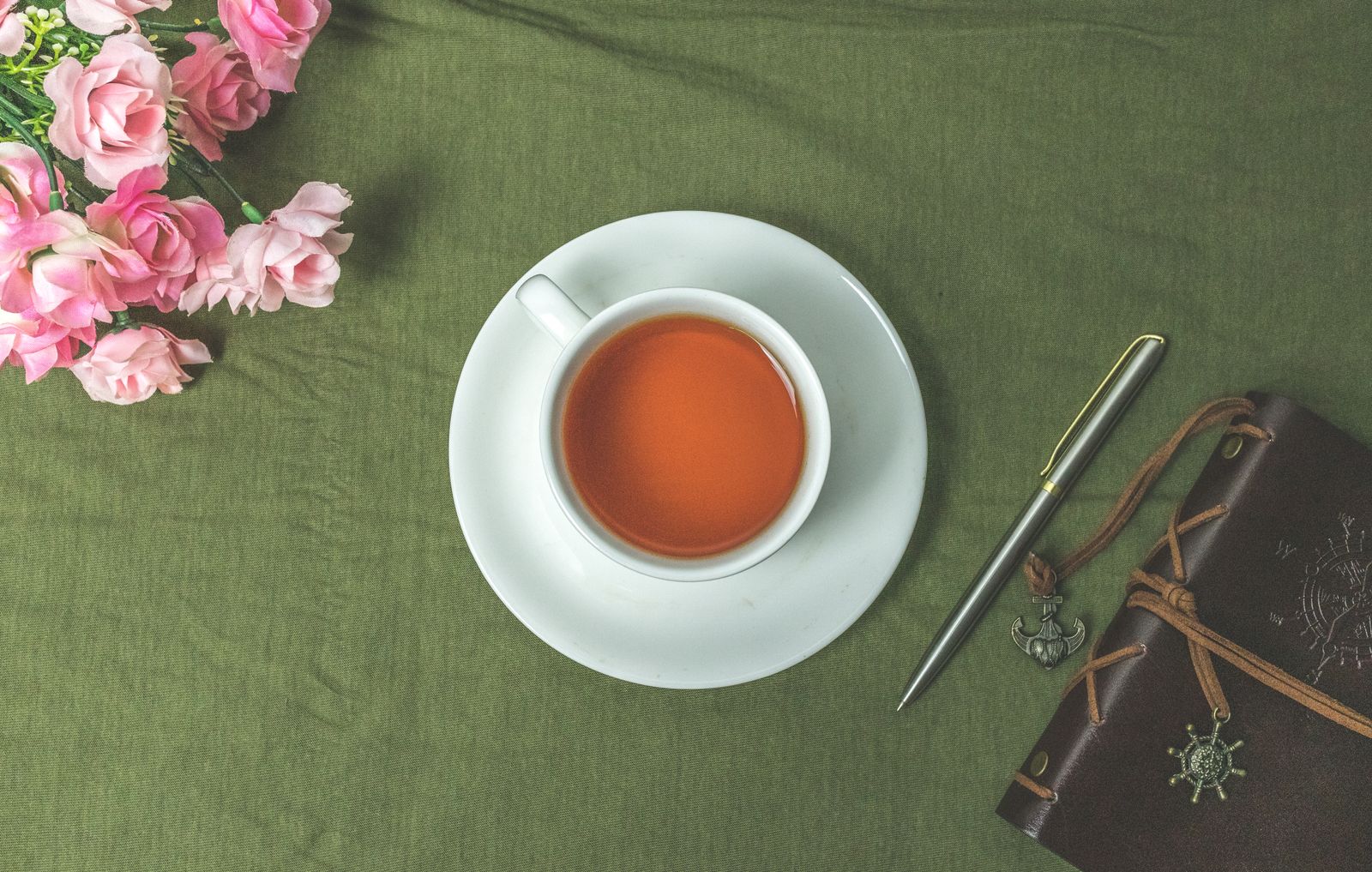 ピンクのバラと紅茶、ペン、革の手帳